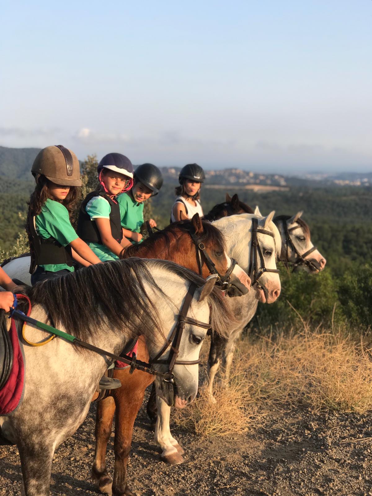 Niños con casco montando ponis en un entorno natural