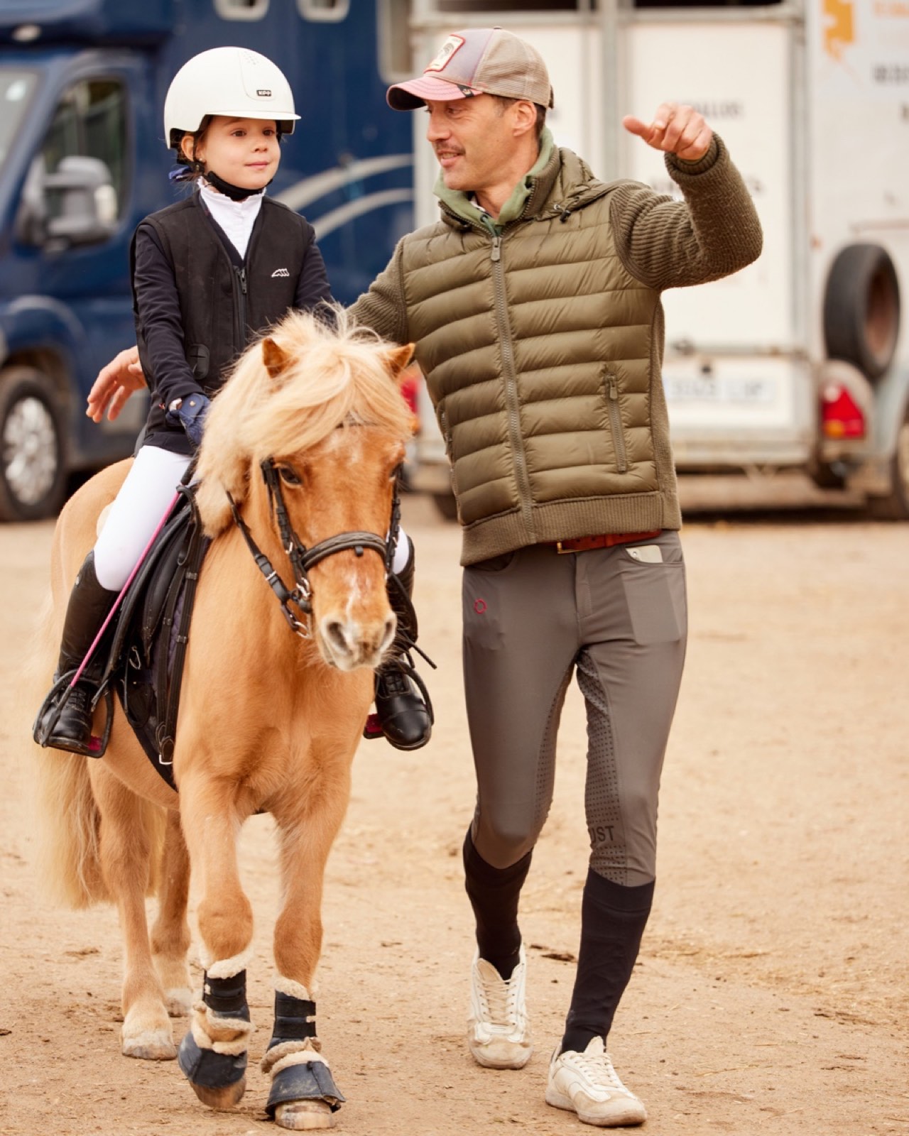 Joven jinete sobre un poni junto a su entrenador